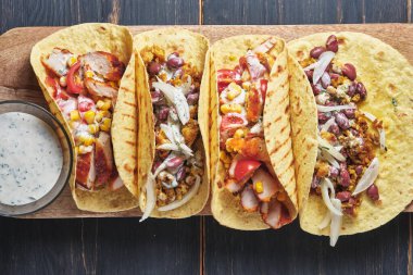 Eski ahşap bir masada etli ve sebzeli Meksika tacoları. Öğle ve akşam yemeği için hızlı sokak yemekleri.