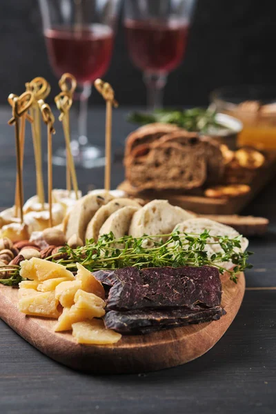 Lezzetli atıştırmalıklar ve şarap. Eski ahşap bir masada çeşitli peynir, fındık, ciabatta ve sosis çeşitleri. Romantik bir akşam yemeği..