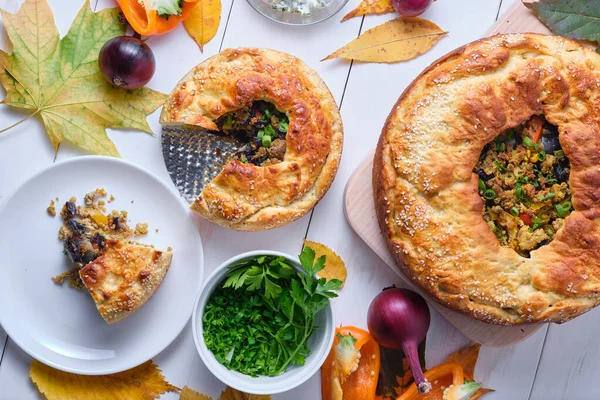 Tabakta et, soğan ve dolmalık biberli ev yapımı sonbahar pastası. Tabak beyaz tahta bir masada. Üst görünüm.