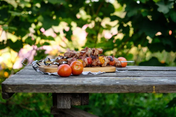 Ahşap bir masada taze pişmiş barbekü. Doğada yaz yemeği. Lezzetli et yemeği ateşte pişmiş..