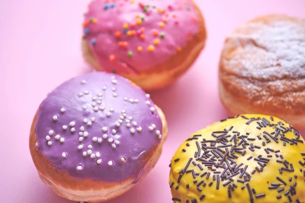 Четыре Пончика Цветной Глазурью Фоне Розовой Бумаги — стоковое фото