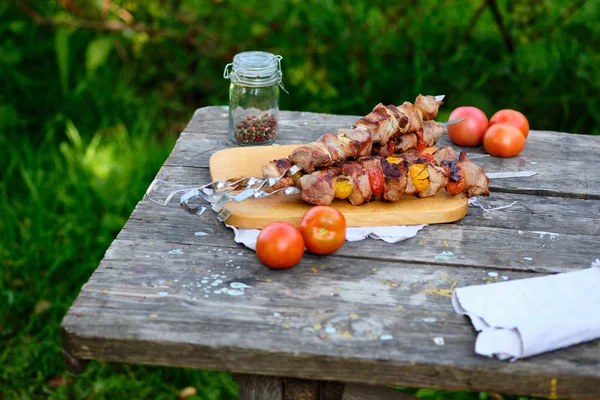 Freshly cooked barbecue on a wooden table. Summer lunch in nature. Tasty meat dish cooked on the fire.