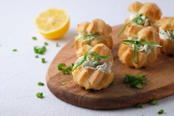 Yumuşak peynirli profiteroller, kırmızı balıklar ve otlar. Tatil masası için gurme yemeği..