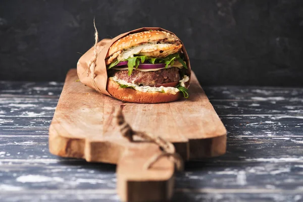 close up of mouth-watering burger with grilled beef patty and fresh vegetables. Tasty american cheeseburger on wooden board. 