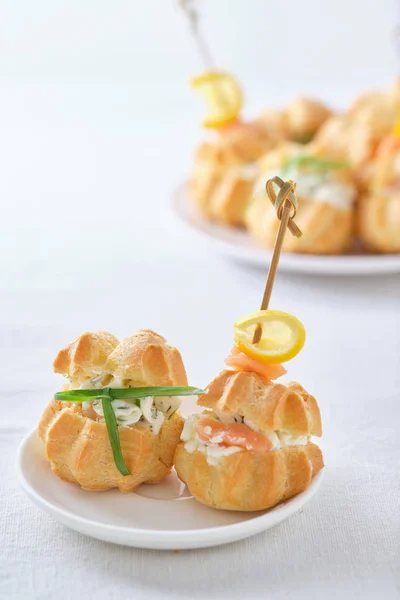 Yumuşak peynirli profiteroller, kırmızı balıklar ve otlar. Tatil masası için gurme yemeği..
