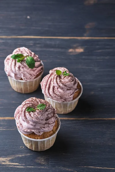 Holiday cupcakes with pink cream. The dessert is decorated with mint leaves and chocolate chips.