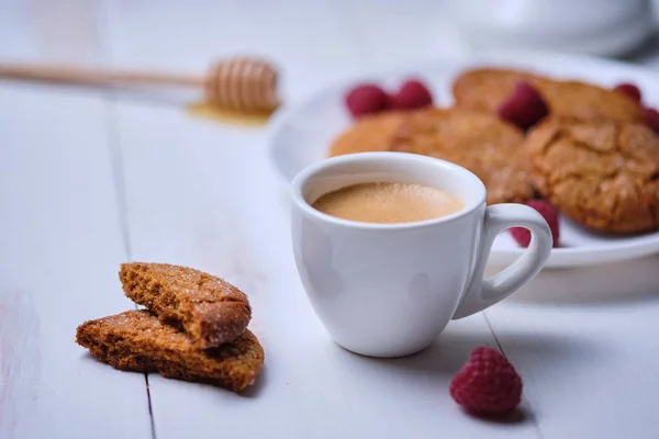 Morning espresso with honey cookies and raspberries. Breakfast on the white kitchen table.