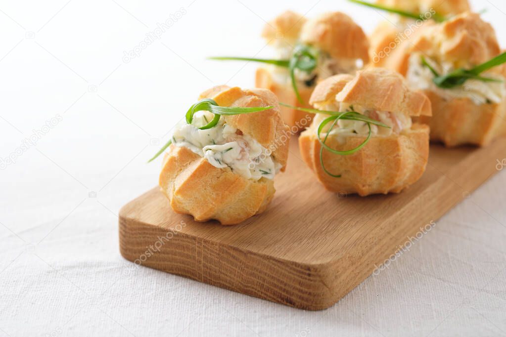 Profiteroles with soft cheese, red fish and herbs. A gourmet meal for the holiday table.