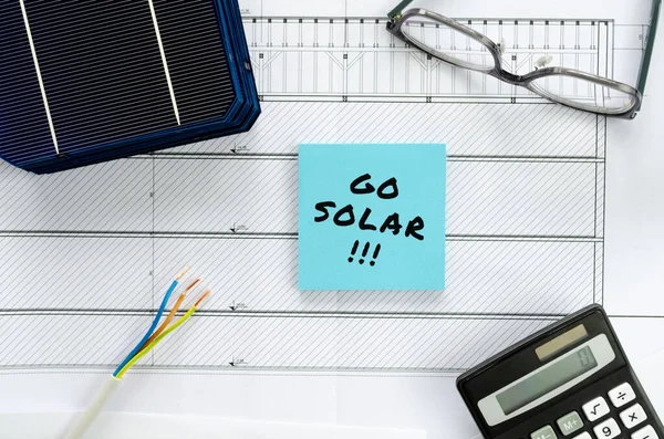 Güneş enerjisine geçişi planlıyorum. Hesap makinesi, gözlük ve kablo ile kavramsal görüntü olarak inşaat planı veya planlama ve güneş pilleri.