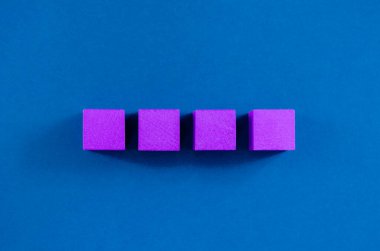 Bir satıra yerleştirilmiş 4 mor tahta blok, kopya alanı, mavi arkaplan üzerine.