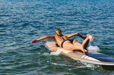 Seksi kadın güvertede uzanmış, el çırpıyor..