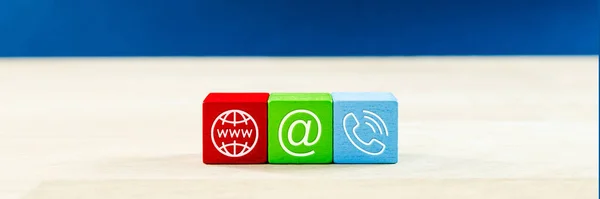 Wide view image of customer service image with three colored wooden dices with contact information icons on them.