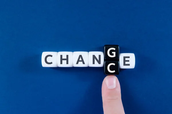 G ve C harflerini değiştiren bir işadamının işaret parmağı beyaz ve siyah küplere yazılmış bir Değişim işaretini Chance 'e dönüştürür..