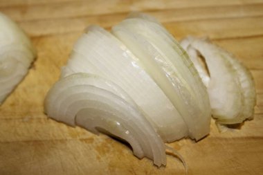 Ahşap kesme tahtası üzerinde kesilmiş soğan dilimleri