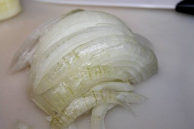 Ahşap kesme tahtası üzerinde kesilmiş soğan dilimleri