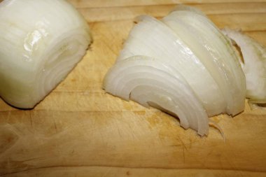 Ahşap kesme tahtası üzerinde kesilmiş soğan dilimleri