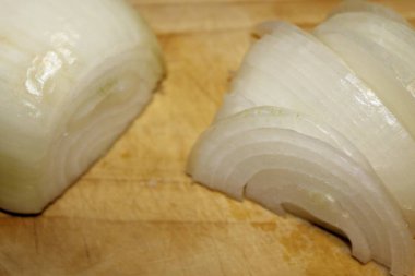 Ahşap kesme tahtası üzerinde kesilmiş soğan dilimleri