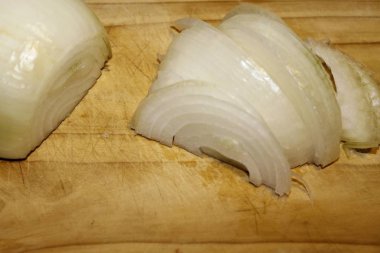 Ahşap kesme tahtası üzerinde kesilmiş soğan dilimleri