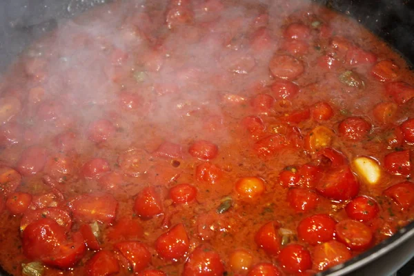 Sauce with fresh cherry tomatoes cooking in pot — Stock Photo, Image