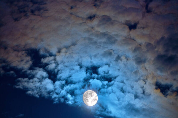 The moon in the sky shines brightly in the night sky in clouds, taken from the telescope with phases of moon.