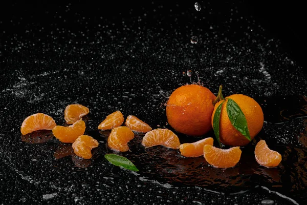 Tangerines mandarines with water drops on black background. New