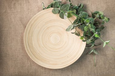 Güzel beyaz seramik tabak ve ahşap arka planda yeşil yapraklar.