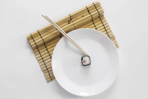 Suşi beyaz arka planda çubuklarla yuvarlanıyor.