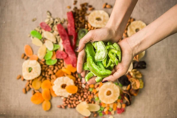 Bir avuç kurutulmuş meyve ve fındık tutan ellerin yakın çekimi.