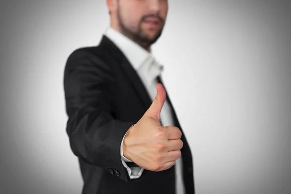 Takım elbiseli ve kravatlı işadamı baş parmağını gösteriyor.
