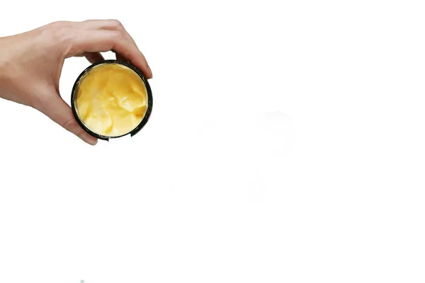 Beyaz arka planda krema kabı olan kadın eli