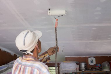 İşçiler tavanda boya silindiri kullanıyorlar.