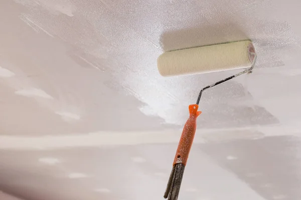 Рабочие используют ролик краски на потолке — стоковое фото