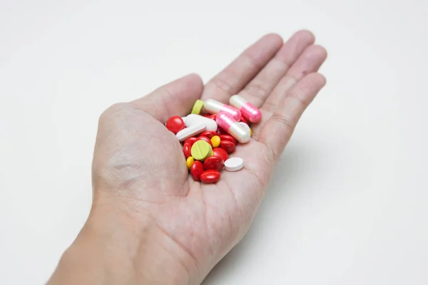 Enfoque selectivo de muchas cápsulas de medicamentos en la mano en la espalda blanca —  Fotos de Stock