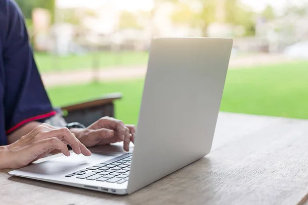 Mujer mano usando computadoras portátiles y tiene un cuaderno y una pluma con cálido — Foto de Stock