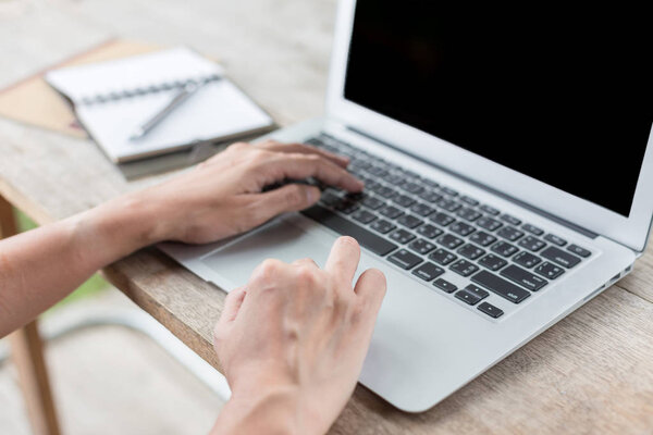 Woman hand using laptops and has a notebook and a pen with warm 