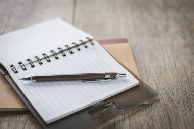 Masadaki kalem, defter ve bardakların seçmeli odak noktası 