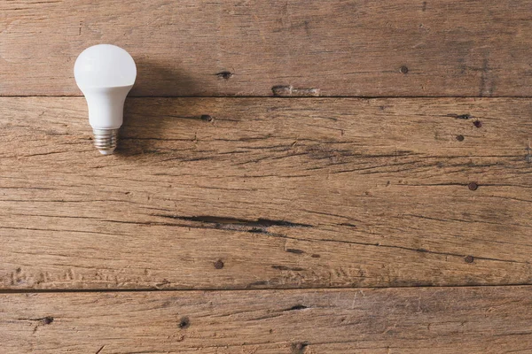 Ahşap arkaplandaki ampulün üst görünümü ve alanı kopyala