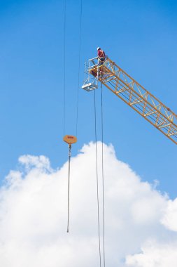 Mavi gökyüzünde büyük bir inşaat vinci üzerinde çalışanlar