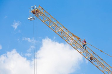 Mavi gökyüzünde büyük bir inşaat vinci üzerinde çalışanlar