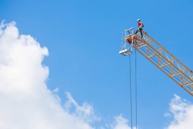 Mavi gökyüzünde büyük bir inşaat vinci üzerinde çalışanlar