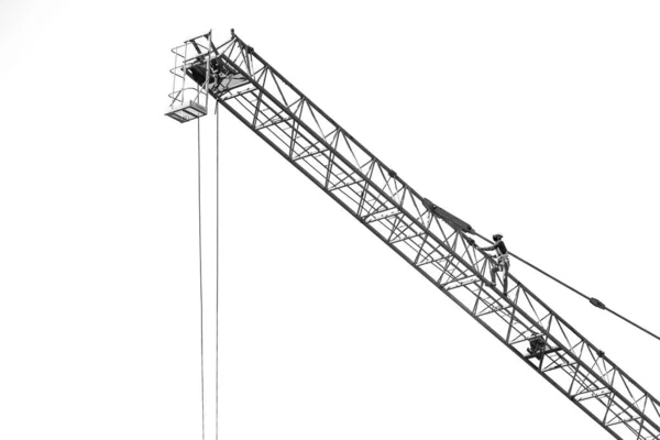 白の上に大きな建設クレーン上の労働者の黒と白 — ストック写真