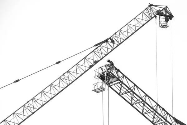 白の上に大きな建設クレーン上の労働者の黒と白 — ストック写真