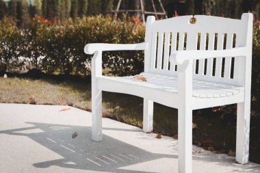 Parktaki beyaz bankta kurur.