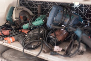 Atölyedeki raflarda birçok eski elektrikli matkap var.