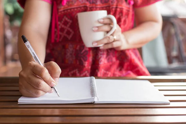 Kvinna Som Håller Penna Skriver Anteckningsbok Och Kaffemugg Ett Träbord — Stockfoto