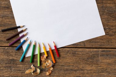 Ahşap arka planda renkli kalem ve beyaz kağıt
