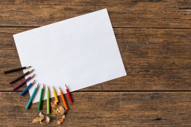 Ahşap arka planda renkli kalem ve beyaz kağıt