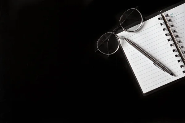 Κάτοψη Του Στυλό Σημειωματάριο Γυαλιά Μαύρο Φόντο Και Αντίγραφο Χώρου — Φωτογραφία Αρχείου
