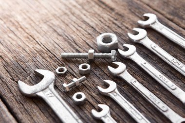 Tahta arka planda somun ve cıvatalı birçok anahtarın seçmeli odağı ve boşluğu kopyala