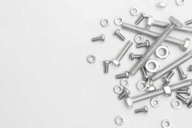 Beyaz arkaplandaki birçok somun ve cıvatanın üst görüntüsü